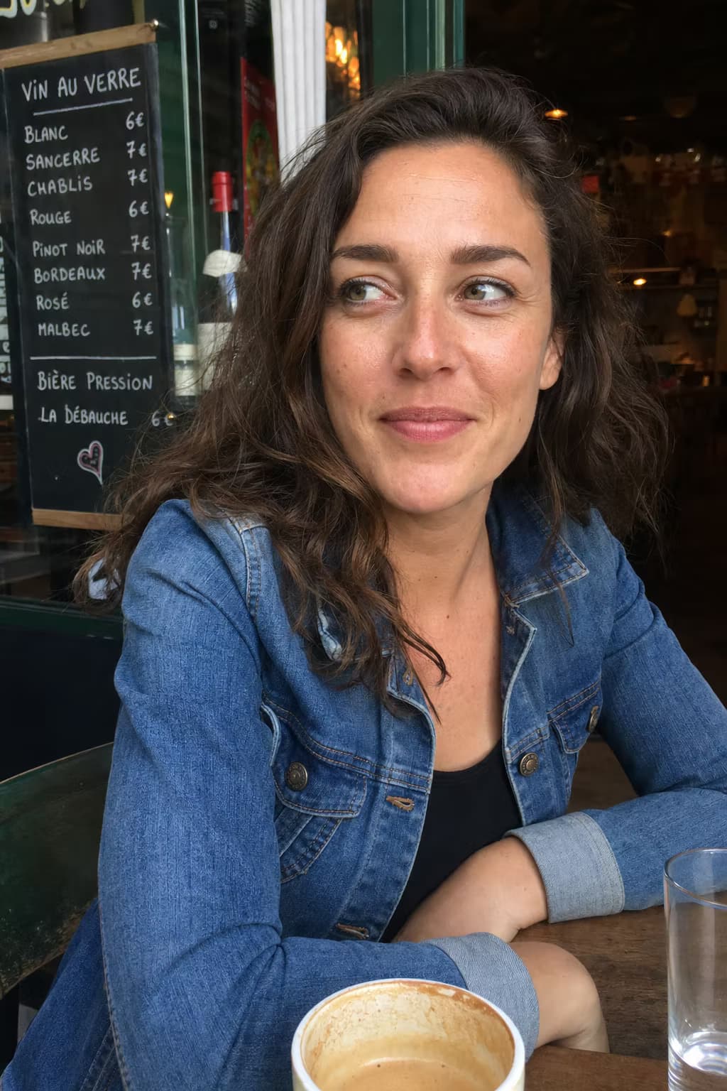 Photo of a woman in a denim jacket smiling in a café — the photo a customer uploaded.